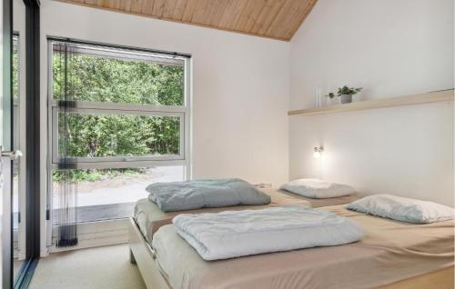 two beds in a room with a window at Rubinsen Skovhuse in Hasle
