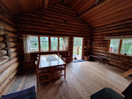 Habitación grande con mesa en una cabaña de madera. en Lakeside wilderness cabin en Jokkmokk