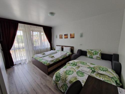 a room with two beds and a table and a window at Pensiunea Bella Vista in Turda