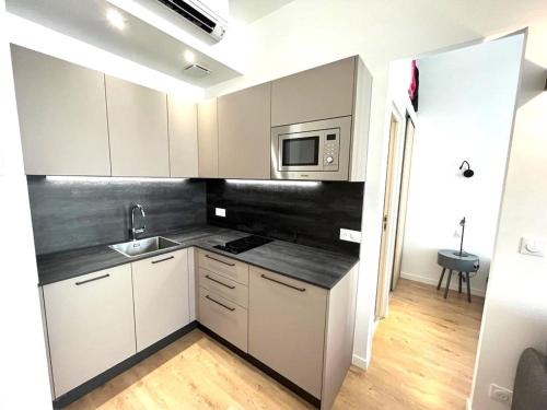 une cuisine avec des armoires blanches, un évier et un micro-ondes dans l'établissement Hypercentre lamartine 404, à Nice