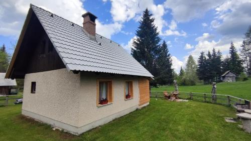 a small house with a gambrel roof on a grass field at Triglav Cottage in Bohinj