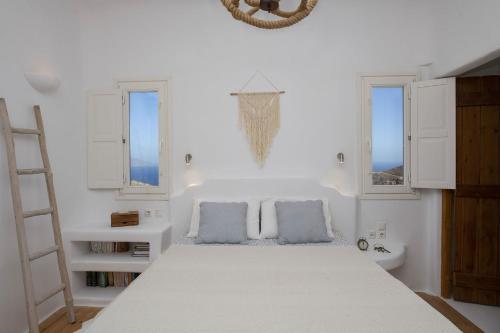 a white bedroom with a bed and two windows at Villa Joy in Fanari
