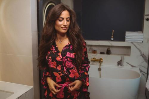 a woman standing in a bathroom in front of a tub at Resto Inn - Smart apartamenty blisko Energylandii in Po”łwieś