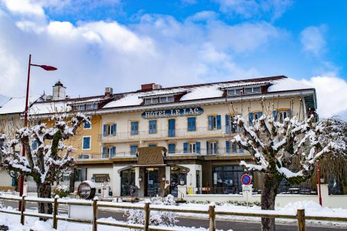 a building with snow covered trees in front of it at Hôtel-Restaurant Le Lac in Malbuisson