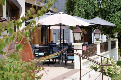 a patio with tables and chairs and umbrellas at Hôtel-Restaurant Le Lac in Malbuisson
