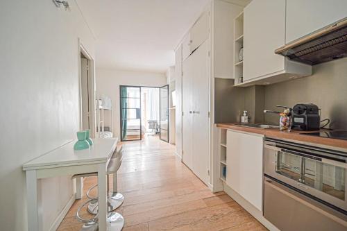 une cuisine avec des armoires blanches et une table à l'intérieur dans l'établissement Warm & Welcoming Flat - Family's Ideal - Marais, à Paris