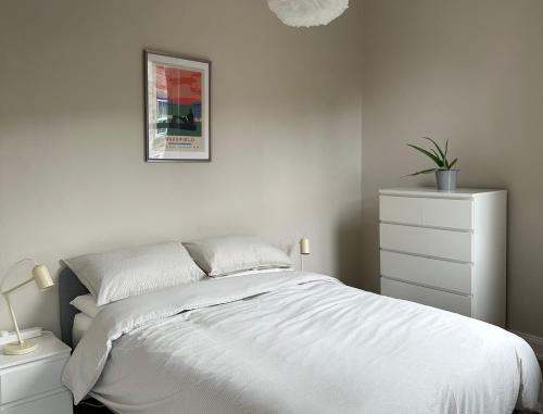 biała sypialnia z łóżkiem i komodą w obiekcie Strawberry Dale Apartment w mieście Harrogate