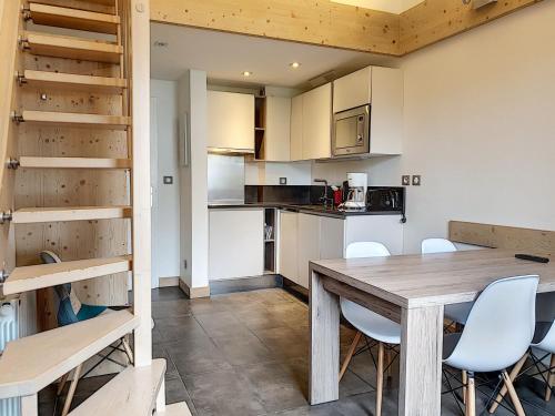 une cuisine et une salle à manger avec une table et des chaises en bois dans l'établissement Studio rénové avec mezzanine, balcon, à 10 min des pistes – Val-d'Isère Centre - FR-1-518-123, à Val dʼIsère