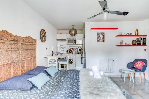 a bedroom with a bed with blue pillows and a kitchen at L Oasis studio proche hôpital et aéroport Piscine Parking &Netflix in Toulouse