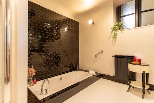 a bathroom with a tub and a black tile wall at Cloe - Hidden Suite in Rome