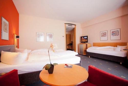 een hotelkamer met 2 bedden en een tafel en stoelen bij Hotel Theresientor in Straubing