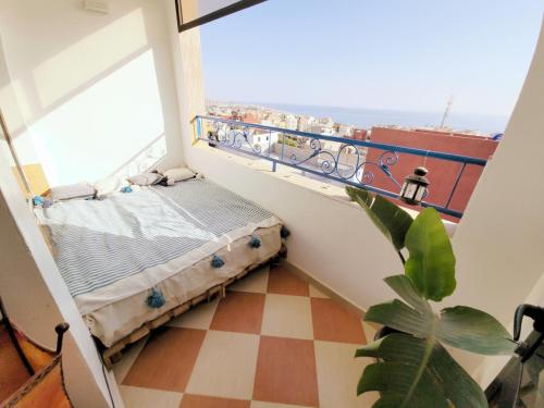 a balcony with a bed in a room with a window at Good Wave Surf House in Tamraght Oufella