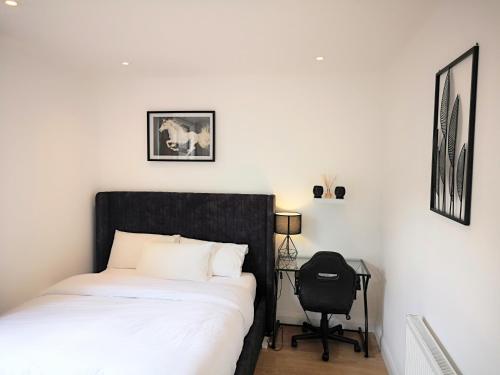 a bedroom with a bed with a black headboard and a chair at Clifton court hemel in Hemel Hempstead