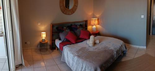 a bedroom with a bed with red pillows and two lamps at Le tamarin bleu - Studio à 300 m de la plage in La Saline les Bains