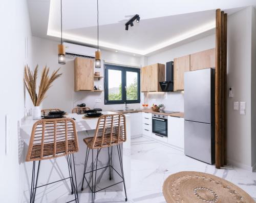 een keuken met een witte koelkast en 2 barkrukken bij Arbona Apartment II in Vóroi