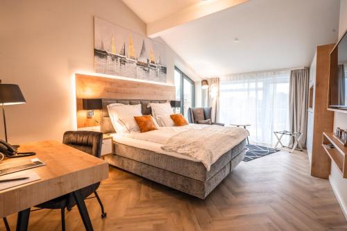 1 dormitorio con 1 cama grande, escritorio y mesa en Hotel MeerZeiten inklusive externer Schwimmbad- & Saunanutzung, en Bensersiel