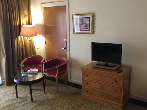 um quarto de hotel com uma televisão numa cómoda com uma mesa em Amarante Pyramids Bed Room no Cairo