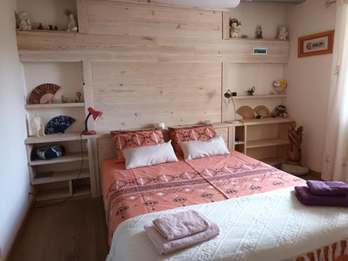 a bedroom with a bed with pink sheets and shelves at maison piscine privée proche de Rodez in Cassagnes-Bégonhès