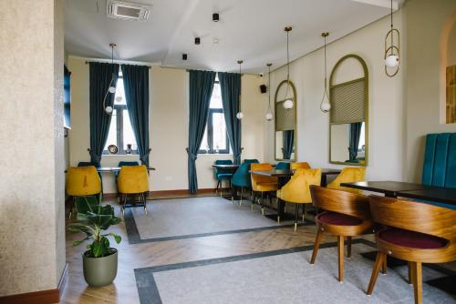 un comedor con mesas, sillas y ventanas en AVIOR Garni Hotel en Subotica