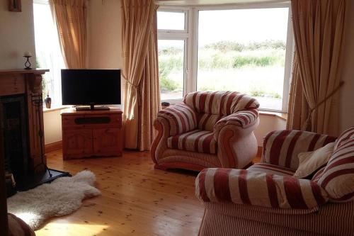 a living room with two chairs and a flat screen tv at Three Sisters Holiday Home - 7km to Dingle in Ballyferriter