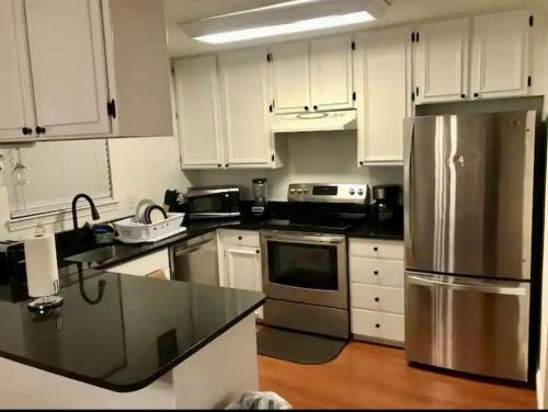 eine Küche mit weißen Schränken und einem Kühlschrank aus Edelstahl in der Unterkunft Room in House - Executive Private Room in Alexandria