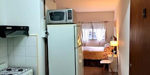 a small kitchen with a microwave on top of a refrigerator at Departamento Centrico Tandil in Tandil