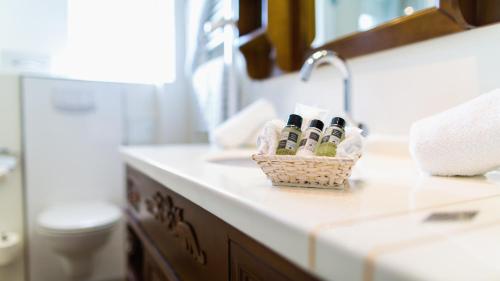 lavamanos en el baño con una cesta de botellas en la encimera en Hotel Holsteiner Hof GmbH en Timmendorfer Strand