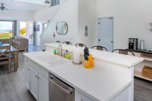 a white kitchen with a sink and a living room at Barefoot Wishes in Oceano