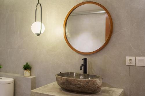 a bathroom with a stone sink and a mirror at Saren Kauh Ubud Palaceॐ in Ubud