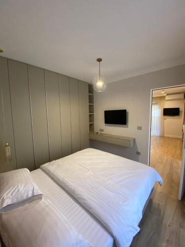 a bedroom with a large white bed and a flat screen tv at Opera Apartments in Cluj-Napoca