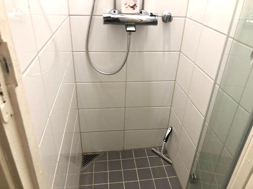 La salle de bains est pourvue d'une douche avec un tuyau et de carrelage blanc. dans l'établissement Sweethome Studio 49 in City Center Punavuori district, à Helsinki