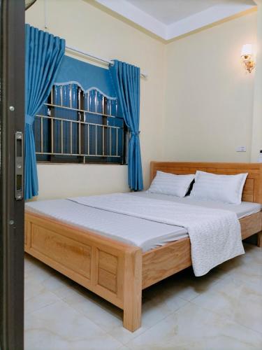 a bedroom with a wooden bed with blue curtains at Hoa Sơn Tra Hotel in Mù Cang Chải