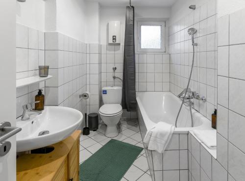a bathroom with a sink and a toilet and a tub at Modern 3-BR Apmt. Sleeps 6+ (Martin-der-Meisterliche) in Essen