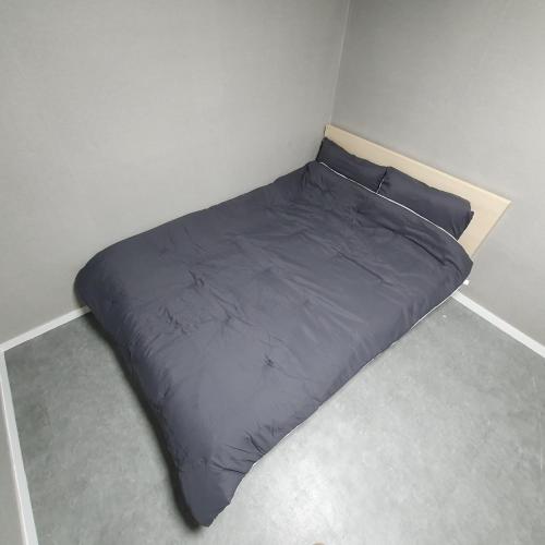 a gray bed in a corner of a room at Seven Hostel in Seoul