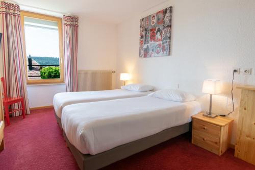 a hotel room with two beds and a window at Hôtel Beau Site in Malbuisson