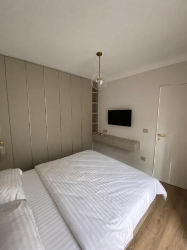 a bedroom with a white bed and a tv at Opera Apartments in Cluj-Napoca