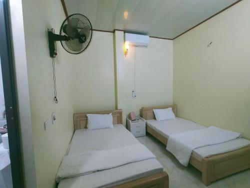a room with two beds and a fan on the wall at Homestay Hoa Sơn Tra in Mù Cang Chải