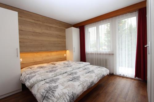 een slaapkamer met een bed en 2 ramen bij Haus Primavera in Saas-Fee