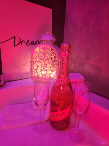 a bottle of wine and two wine glasses on a table at WARSZAWA CENTRAL HOUSE - Studios in Warsaw with Private Jacuzzi, full access to Sauna, Gym and Billards - Studia z prywatnym Jacuzzi oraz dostępem do sauny, siłowni i bilarda in Warsaw