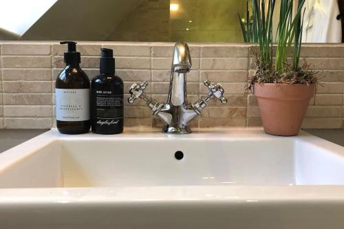 two bottles of wine are sitting on a sink at Romantic cosy cottage close to Oxford and The Cotswolds in Cuddesdon