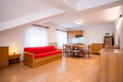 un soggiorno con divano rosso e una cucina di Residence Villa Viola ad Andalo