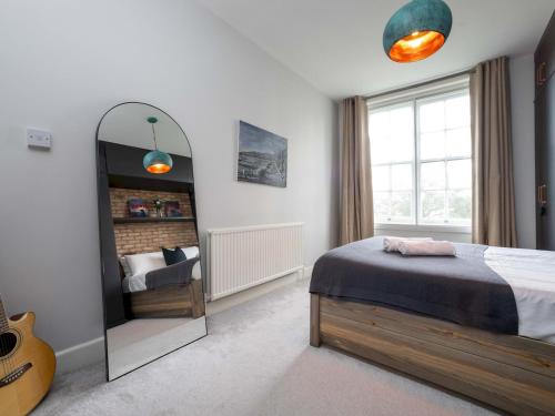 una camera da letto con specchio, letto e chitarra di Pass the Keys One bedroom APT near popular London attractions a Londra