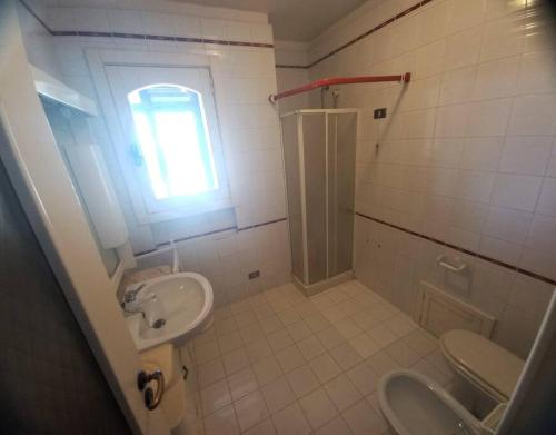 ein Bad mit einem Waschbecken, einem WC und einem Fenster in der Unterkunft Tropical Garden in Lequile