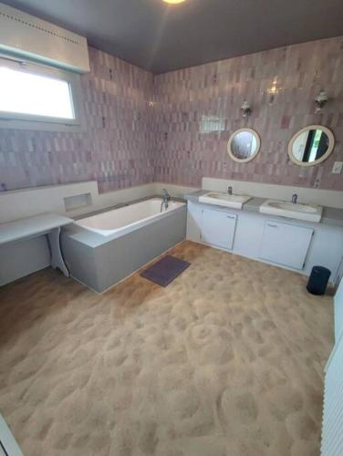 La grande salle de bains est pourvue d'une baignoire et de 2 lavabos. dans l'établissement Gite LE 45 TOURS, à Nueil-sous-les-Aubiers