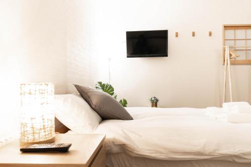 a bedroom with a white bed with a television on the wall at 鶴橋妙宅 in Osaka