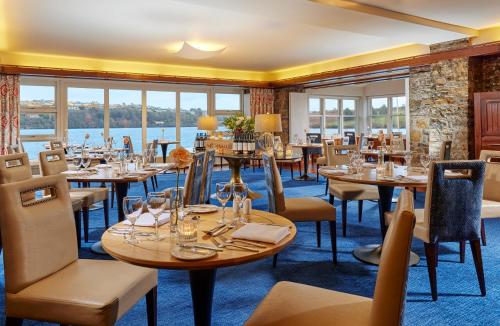 ein Restaurant mit Tischen und Stühlen und Blick auf das Wasser in der Unterkunft Trident Hotel Kinsale in Kinsale