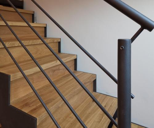 a staircase with wooden stairs and a metal railing at Filder-Appartements in Filderstadt