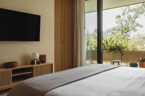 a bedroom with a large bed with a large window at Teva Tulum, Aldea Zamá in Tulum