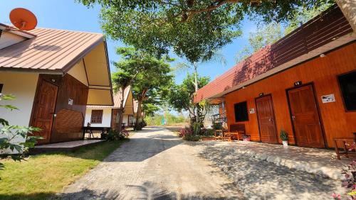 a dirt road next to a building with a house at Bansuanphuhong Resort in Chiang Khan
