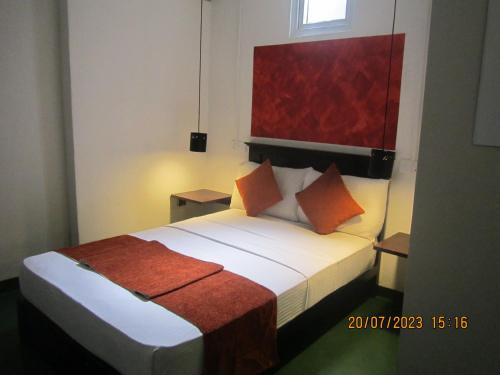 キャンディにあるMy city Bedsのオレンジの枕が付くベッドが備わるホテルルームです。